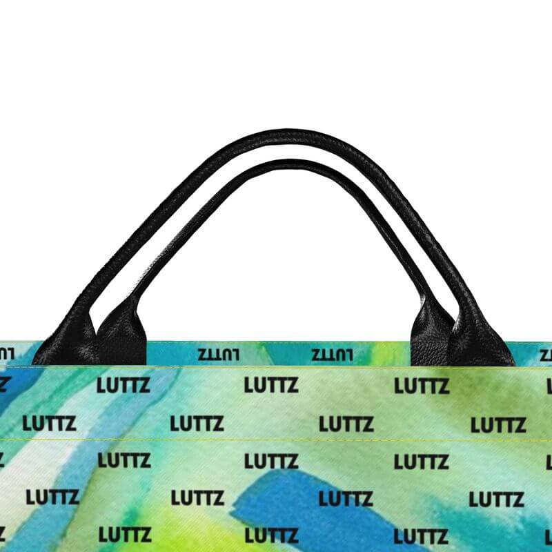 Colorful LUTTZ beach bag featuring a unique Mediterranean fabric design, black leather handles, and a joyful abstract pattern.
