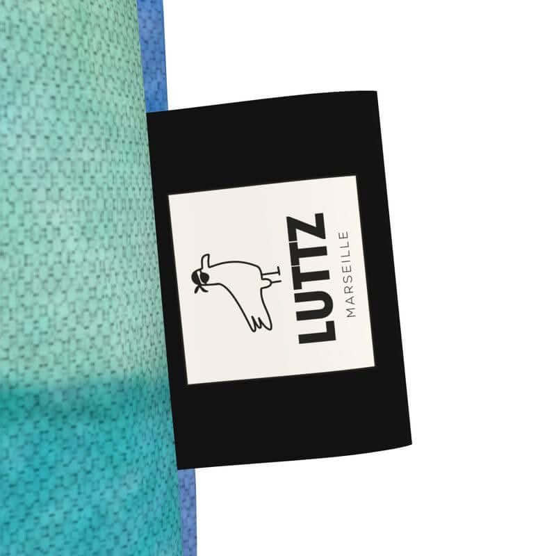 LUTTZ brand tag featuring unique artwork design, showcasing luxury cotton denim from Marseille, inspired by Mediterranean aesthetics.