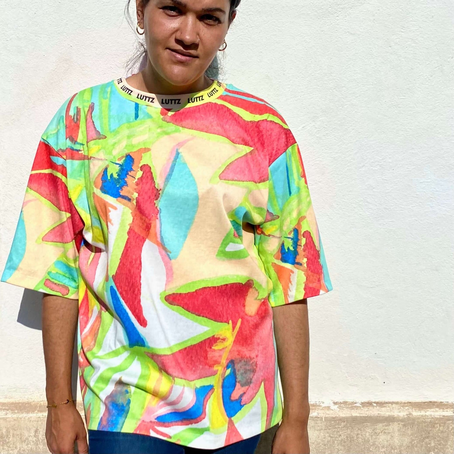 young woman with Luttz luxury oversize t-shirt standing at la Plaine. Unique, original and colorful design creation, like a piece of art, artwork, abstract painting.