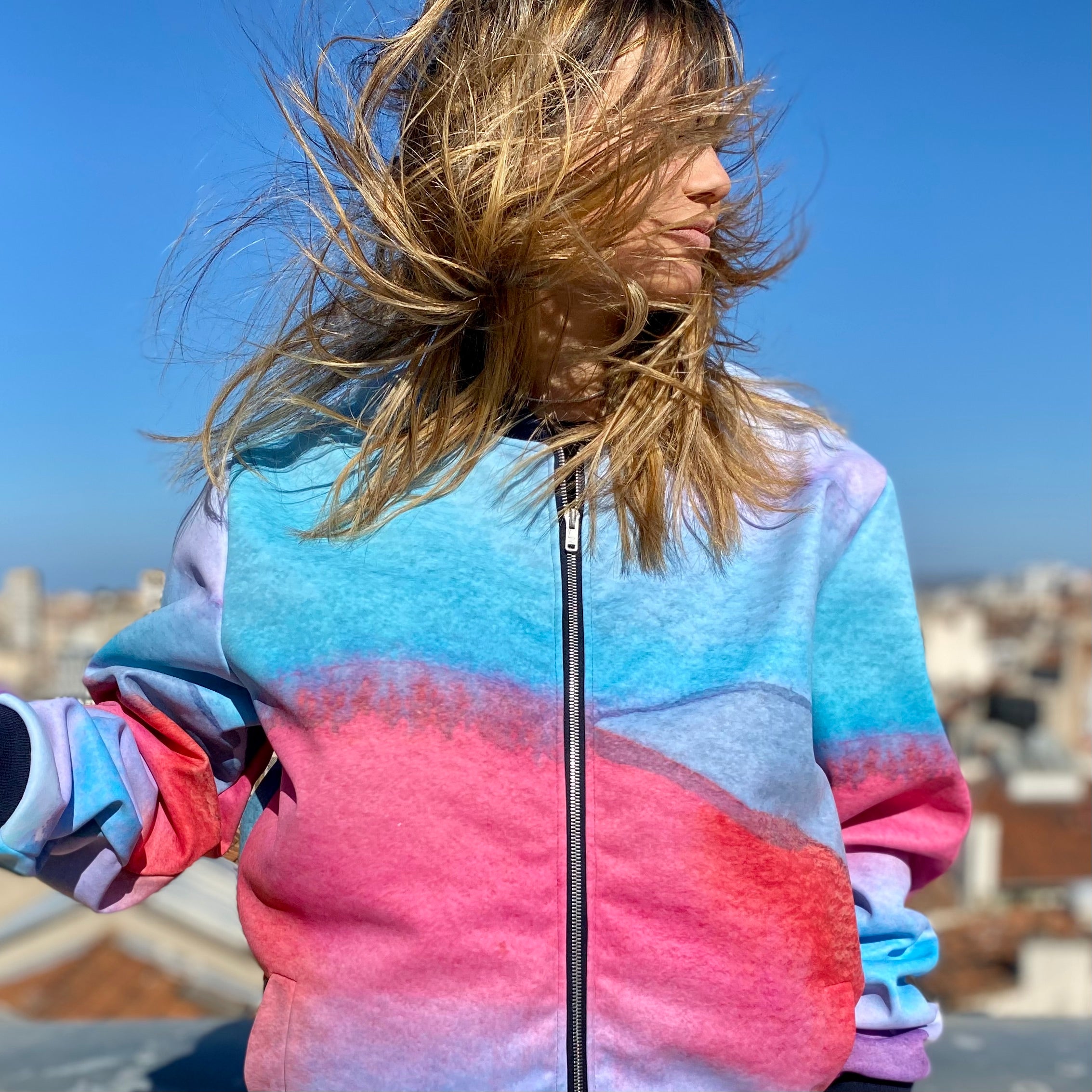 Person wearing a colorful jacket with a citysky in the background
